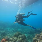 Diver descending in clear water below the boat, Red Pillar scuba diving, Havelock Island