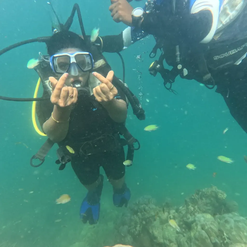 Diver making hand signs with small reef fish nearby, scuba diving in Havelock Island