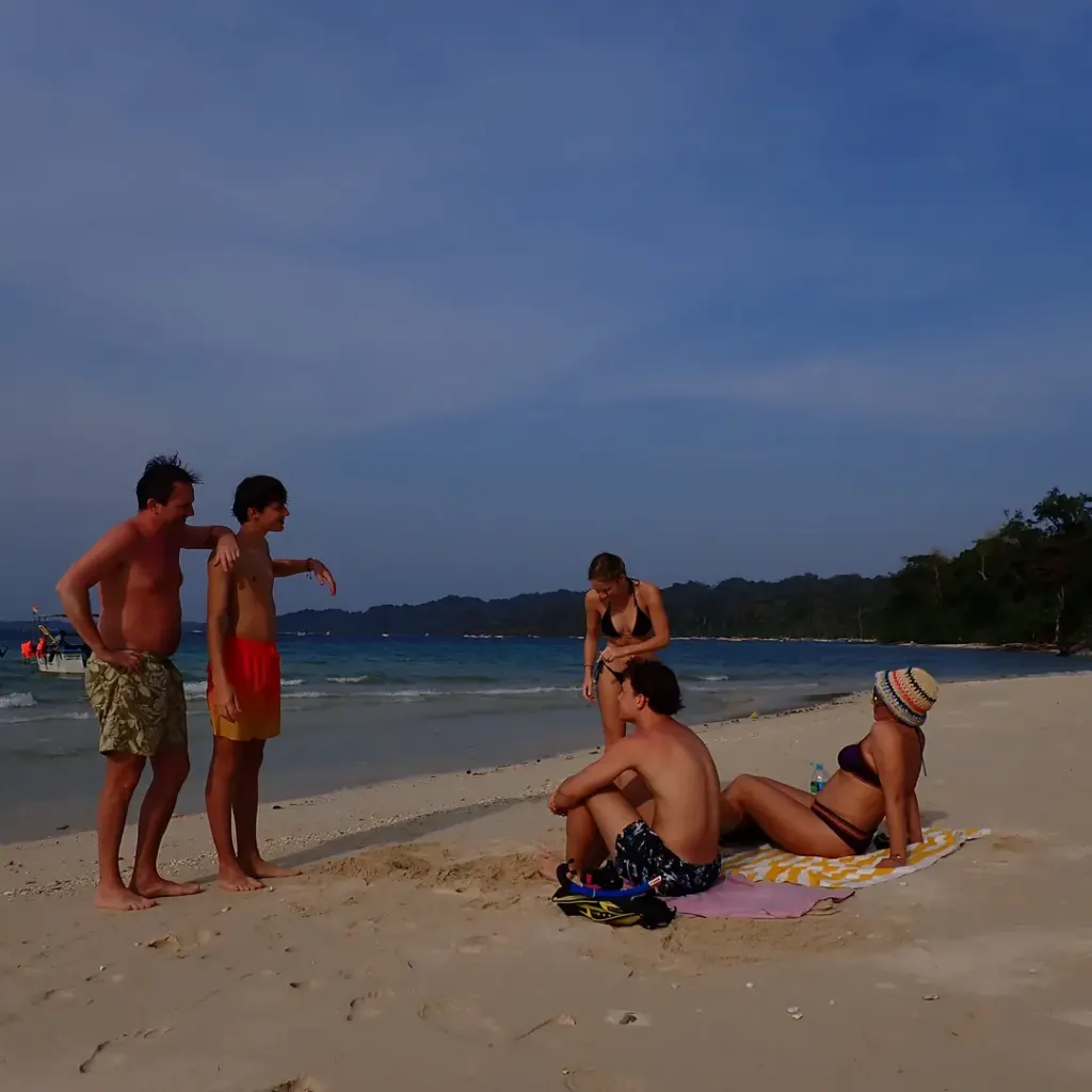 Group of friends on a white sand beach with forest behind, a boat day trip from Havelock