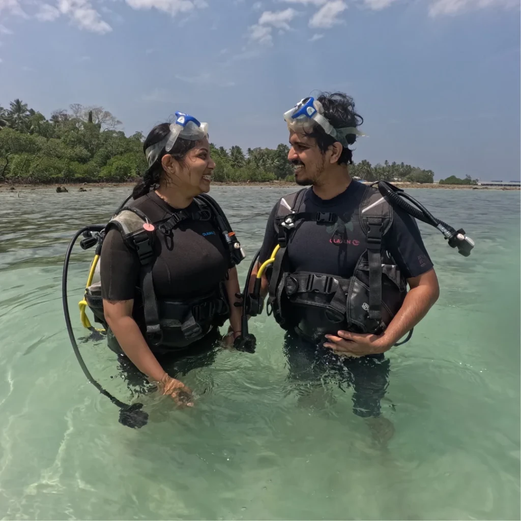 Couple shore scuba diving in Havelock, Andaman standing in calm shallow water