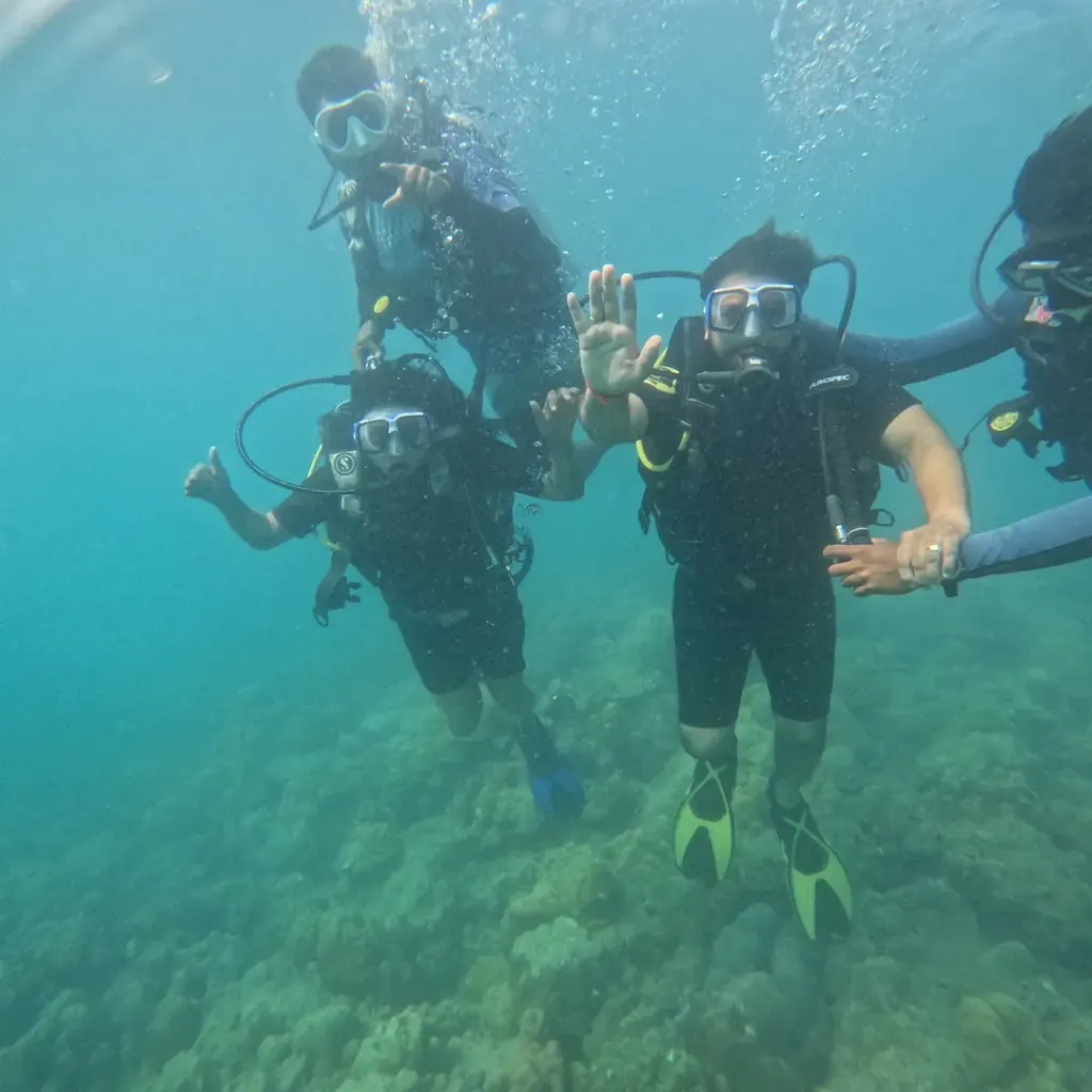 Group of four divers over the reef, RAID Divemaster course in Havelock, Andaman