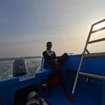 Person sitting at the back of the dive boat in morning light, Nitrox course in Havelock, Andaman