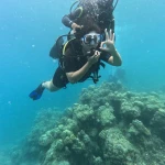 Diver making a hand sign above the reef in blue water, fun diving in Havelock Island