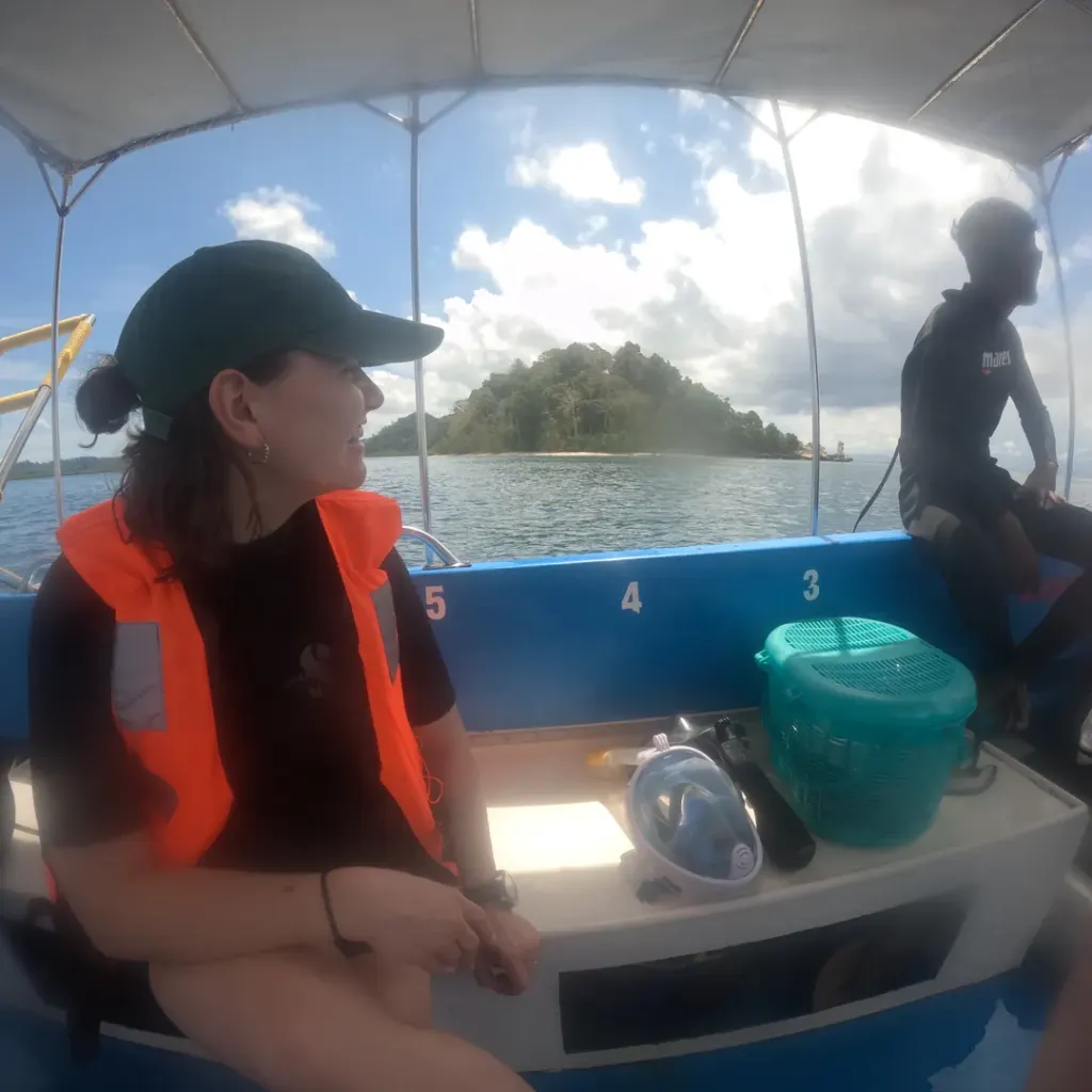 Guest in a life jacket on the boat with an island behind, fun diving in Havelock Island