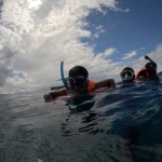 Snorkellers at the surface under a cloudy sky, island hopping from Havelock