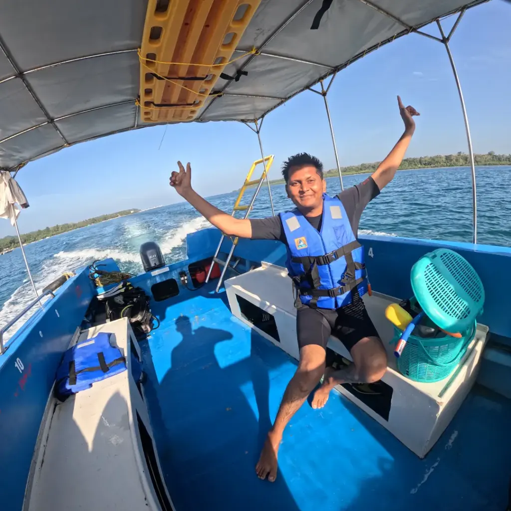 Guest with arms raised on the boat as it speeds along, island hopping from Havelock