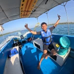 Guest with arms raised on the boat as it speeds along, island hopping from Havelock