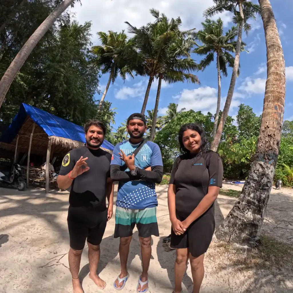 Three guests on a beach with palm trees and a hut, island hopping in Andaman