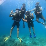Group of four divers posing together in blue water, Lighthouse scuba diving, Havelock Island
