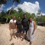 Group of four on a sandy beach under palm trees, a boat day trip from Havelock