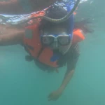 Snorkeller in a mask and life jacket looking down, snorkelling in Havelock Island