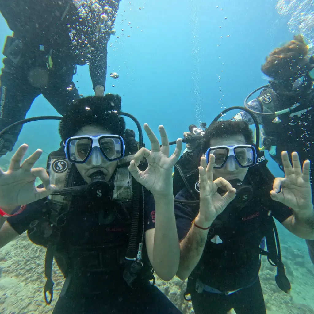 Two friends giving the OK sign underwater during a Nemo Beach scuba diving trip in Havelock