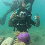 Diver making hand signs above a purple anemone, scuba diving in Havelock Island