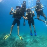 Group of four divers posing in blue water, RAID Divemaster course in Havelock, Andaman