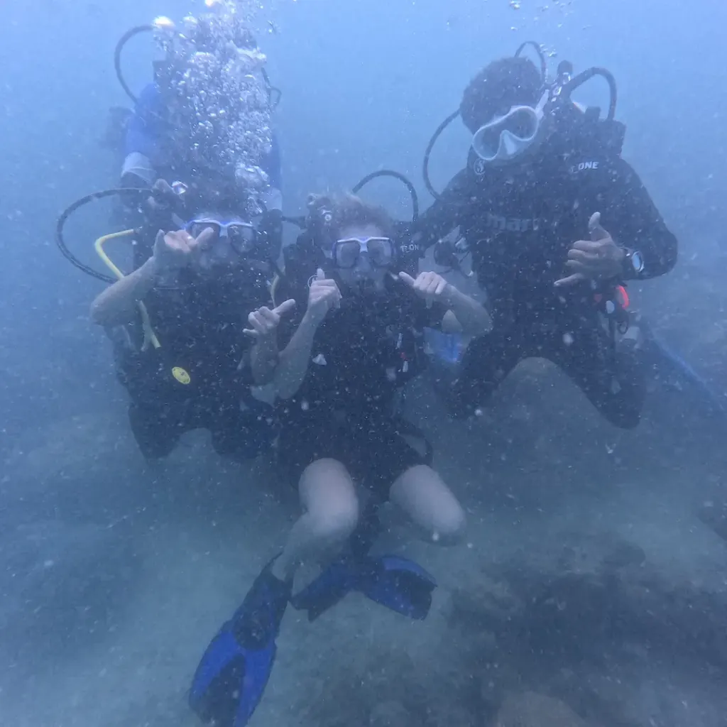 Group of three divers making hand signs, RAID Divemaster course in Havelock, Andaman