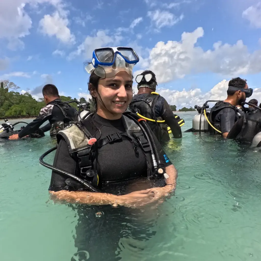 Guest in scuba gear in shallow water with others training behind, RAID Open Water course in Havelock, Andaman