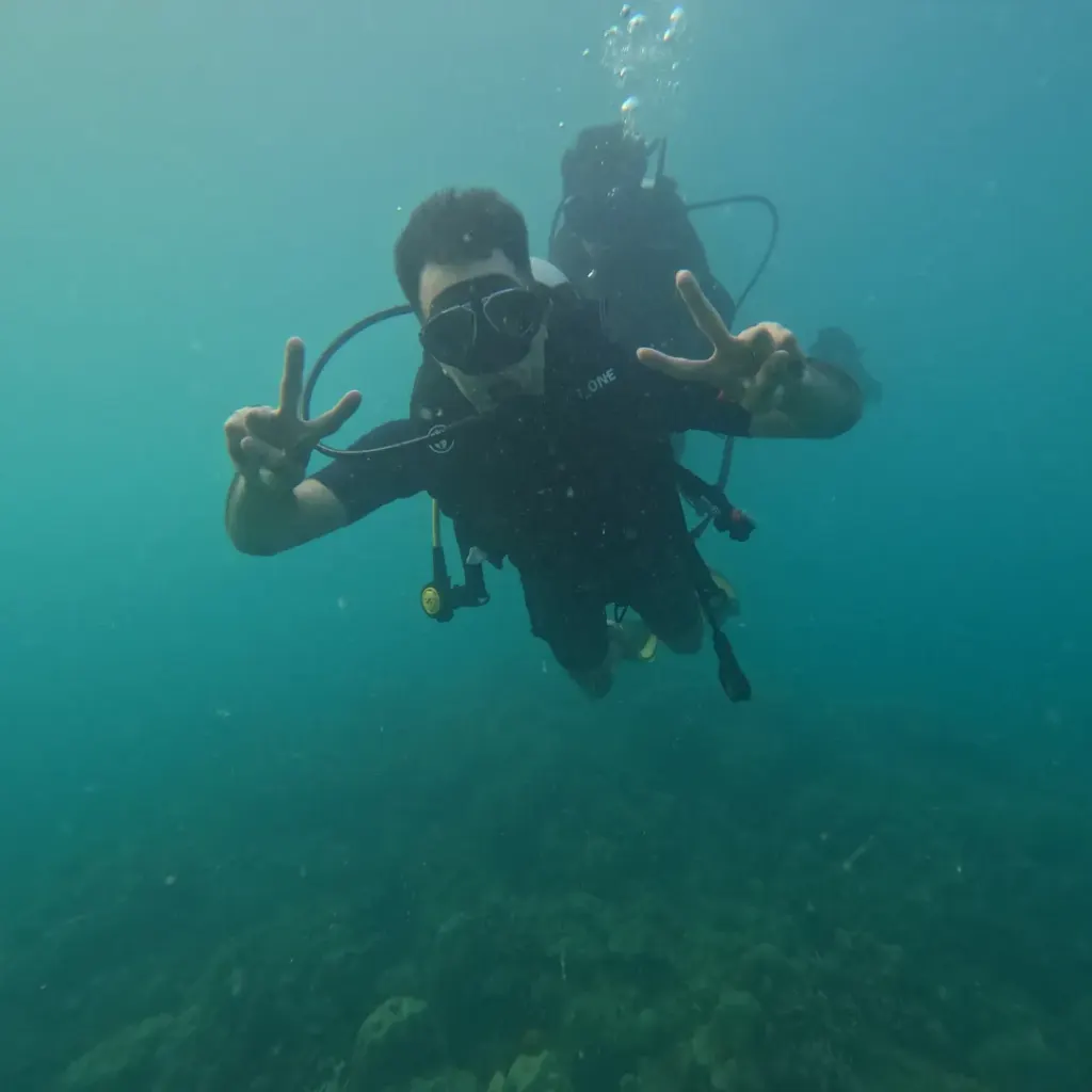 Diver making a peace sign in green water, RAID Master Rescue Diver course in Havelock, Andaman