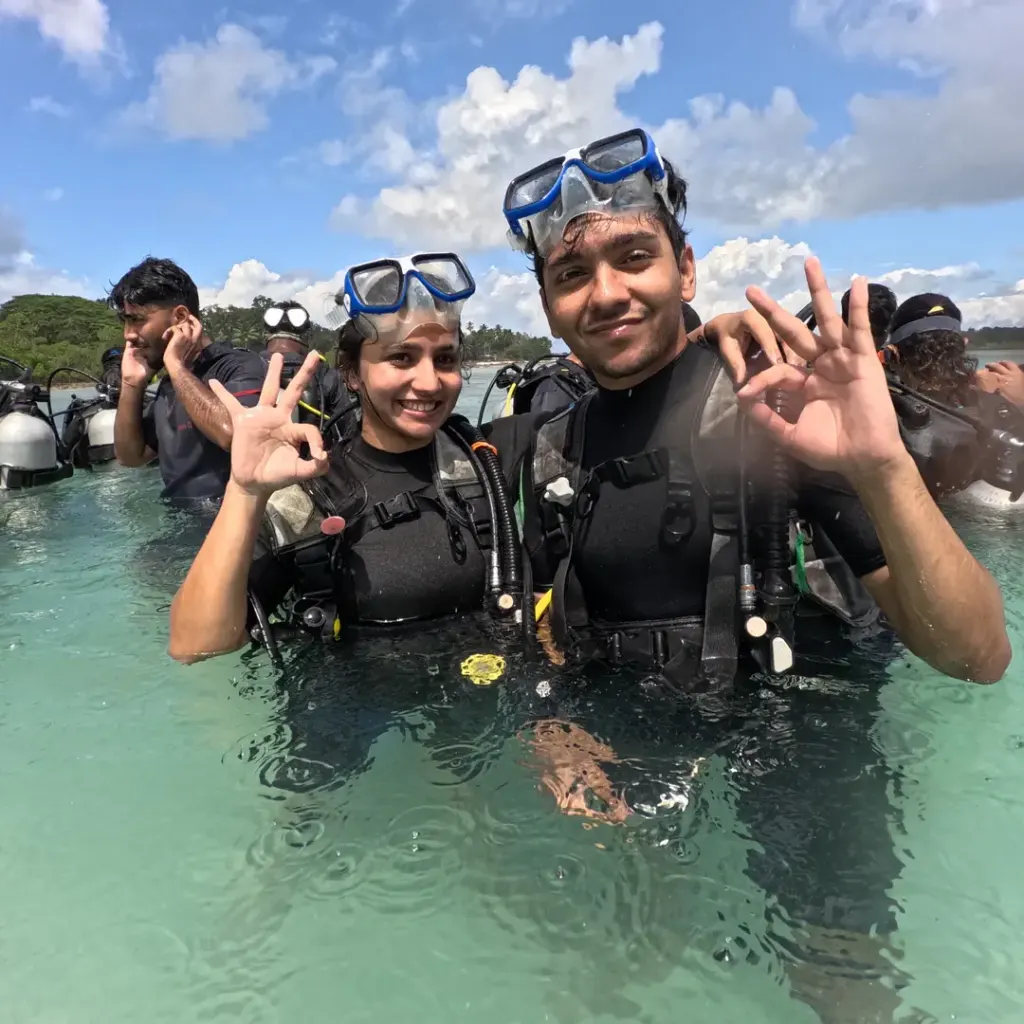 Two guests in scuba gear making hand signs in shallow water, Try Scuba diving in Havelock Island