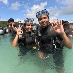 Two guests in scuba gear making hand signs in shallow water, Try Scuba diving in Havelock Island