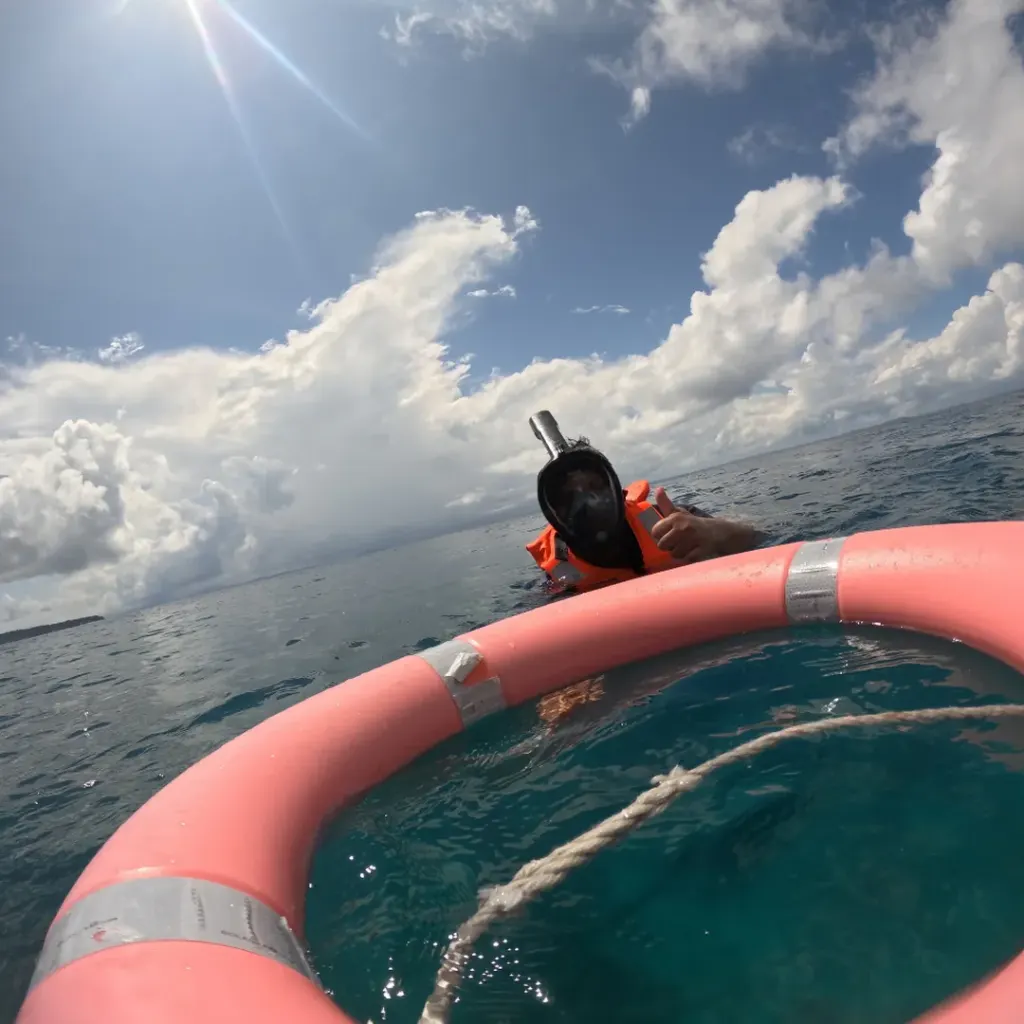 Snorkeller resting by the float ring on the open sea, a boat trip from Havelock