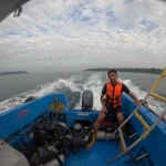 Guest in a life jacket at the back of the boat with the wake behind, a boat trip from Havelock