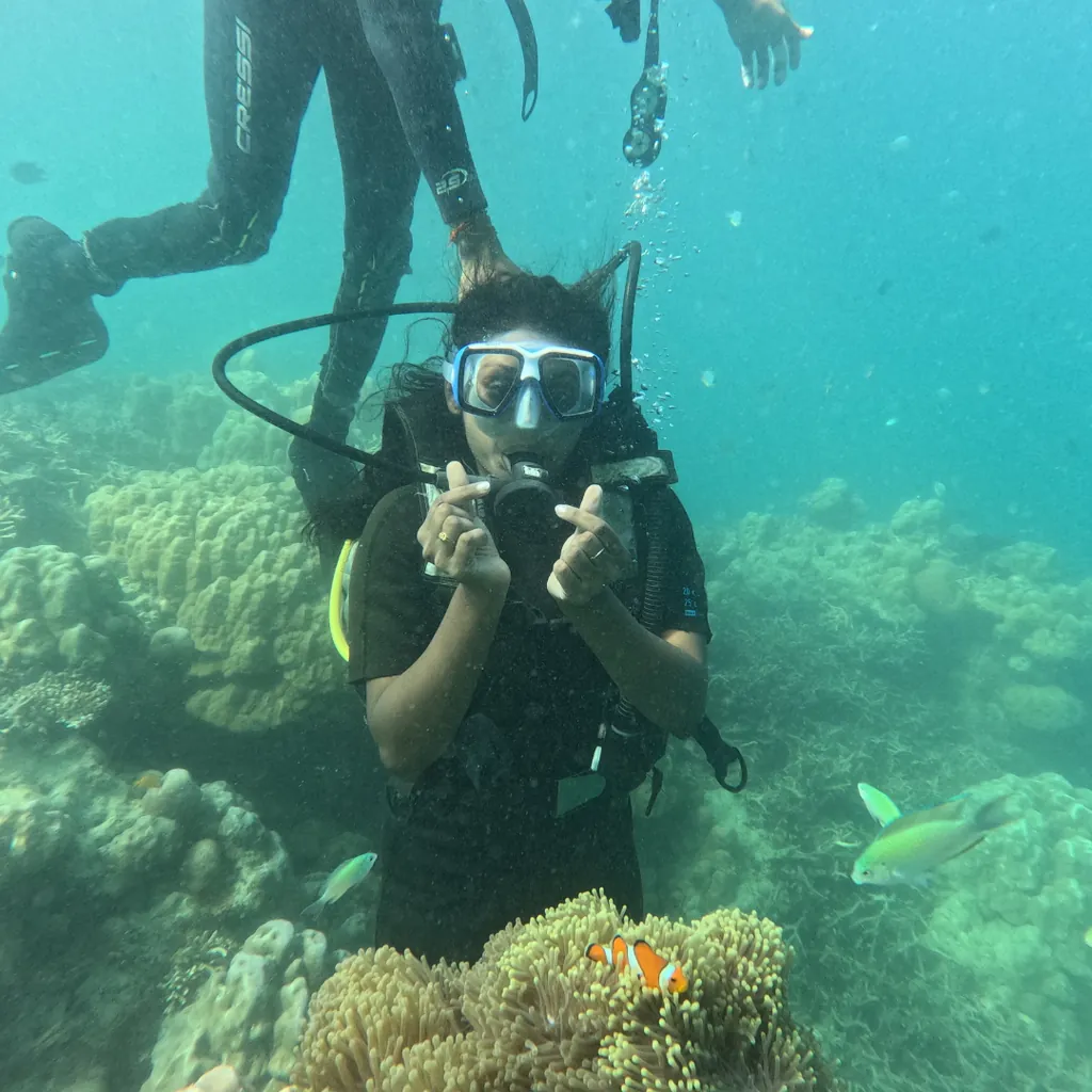 Diver hovering above an anemone with a clownfish while scuba diving at Tribe Gate, Havelock Island