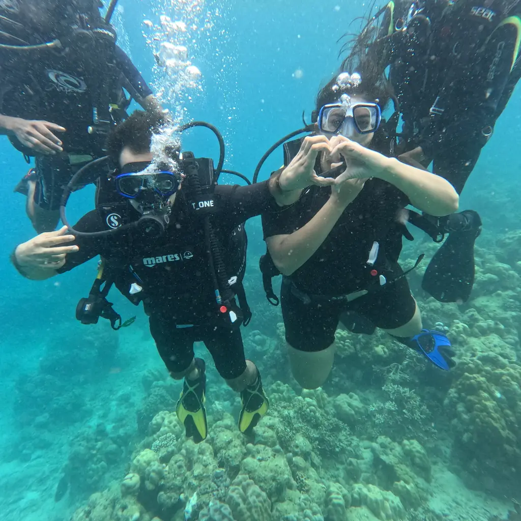 Couple posing with a heart sign underwater during a Tribe Gate scuba dive in Havelock