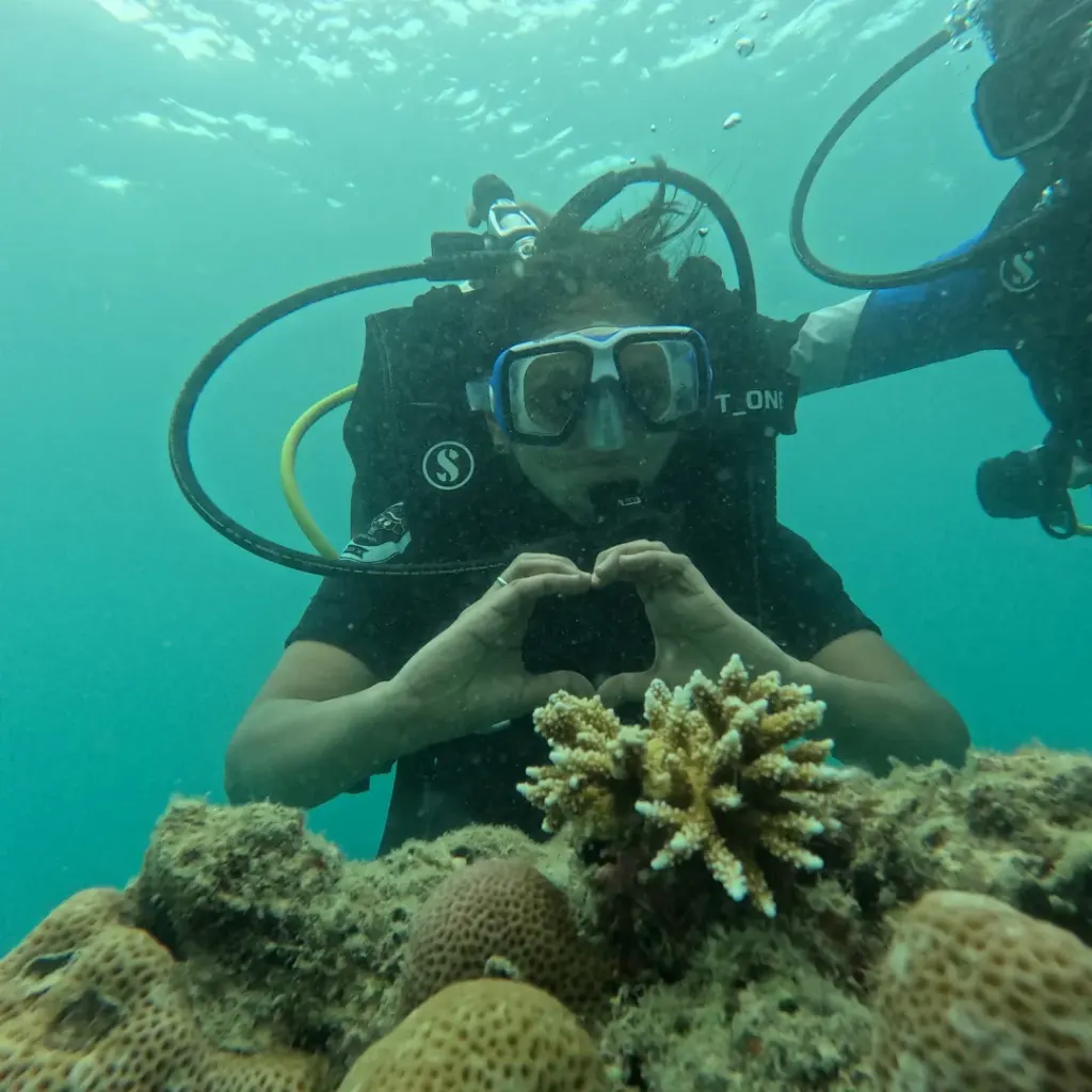 Diver making a heart sign above branching coral, Turtle Beach scuba diving, Havelock Island