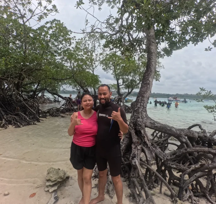 Couple on the beach beside the mangrove roots at Havelock