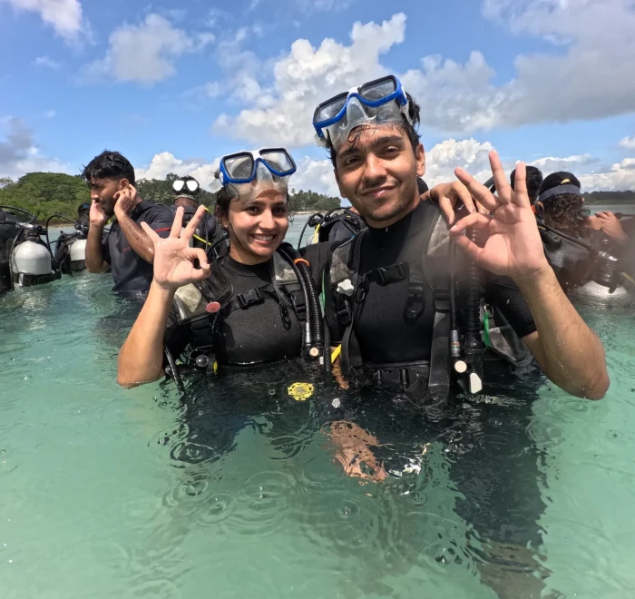 Couple giving OK signs in the shallows before their dive
