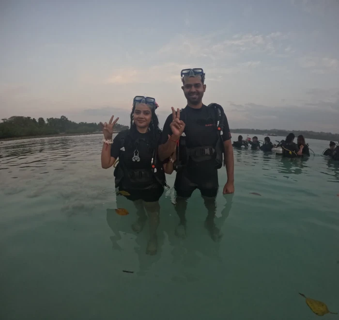 Couple giving peace signs in the shallows with the group behind