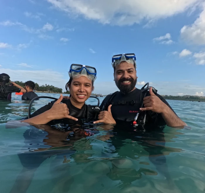Couple giving shaka signs in the shallows before their dive