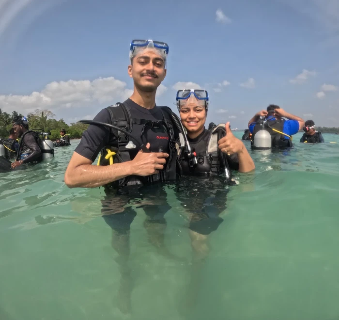 Couple giving thumbs up in the shallows before their dive