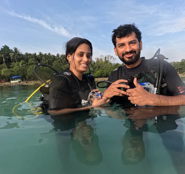Couple making a heart shape in the shallows before their dive