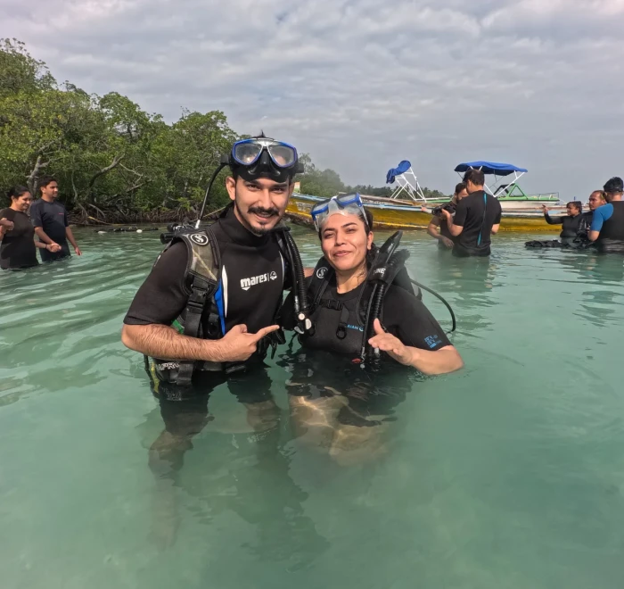 Couple in the shallows with the dive boats moored behind at Havelock Island