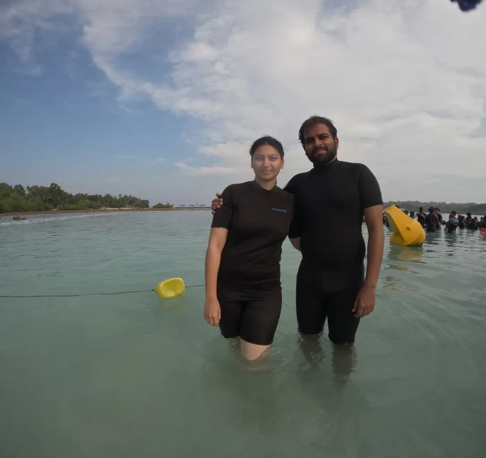 Couple standing in the shallows with the beach behind