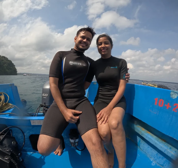 Couple in wetsuits on the dive boat before their dive