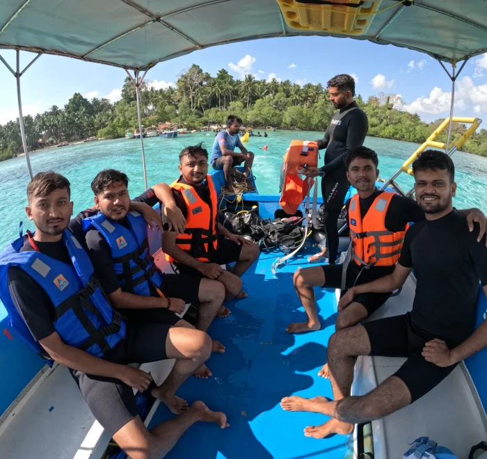 Dive group in life jackets on the boat with the island behind