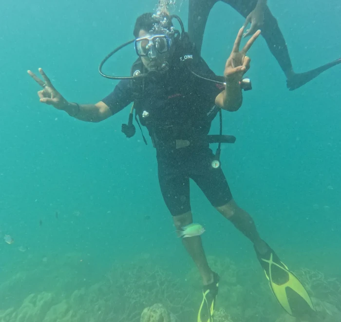 Diver with arms out giving peace signs underwater