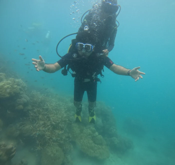 Diver with arms outstretched above the reef