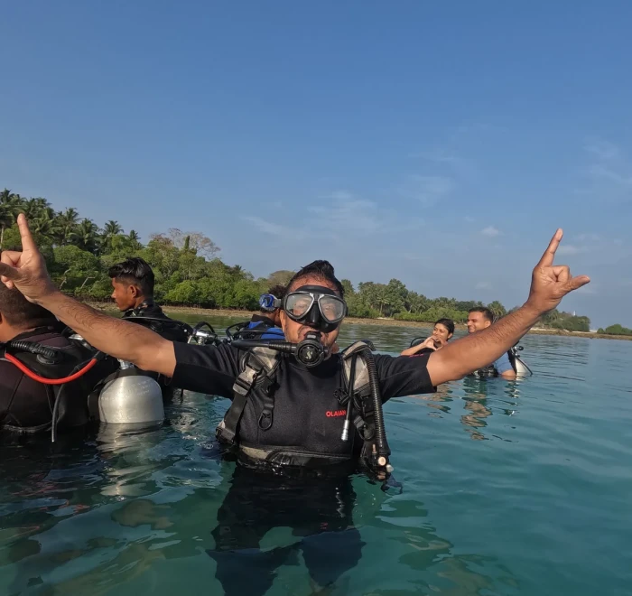 Diver celebrating with both arms up in the shallows after a dive