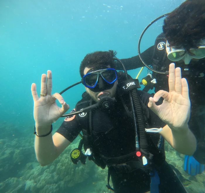 Diver giving OK signs with both hands beside the dive guide
