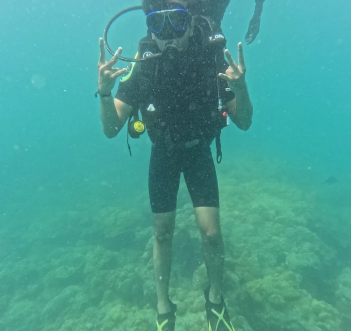 Diver giving peace signs above the coral