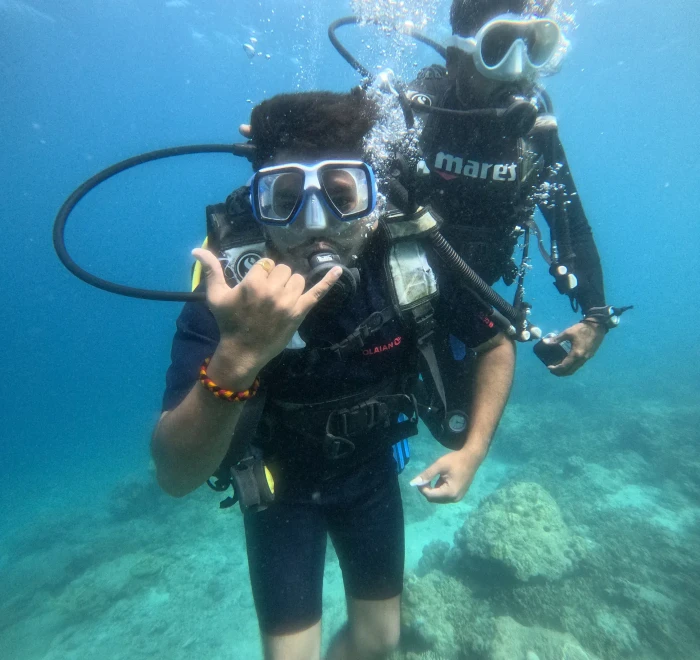 Diver giving a shaka sign close to the camera underwater