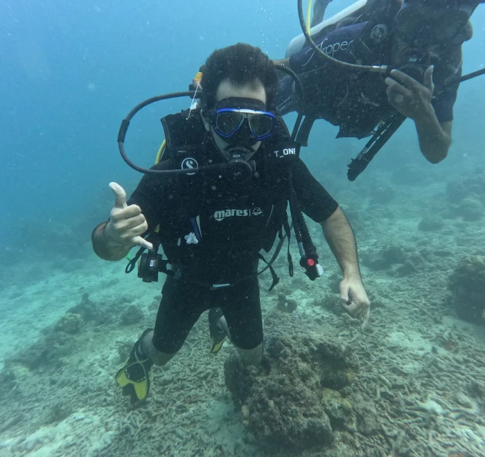 Diver giving a thumbs up above the reef in clear water