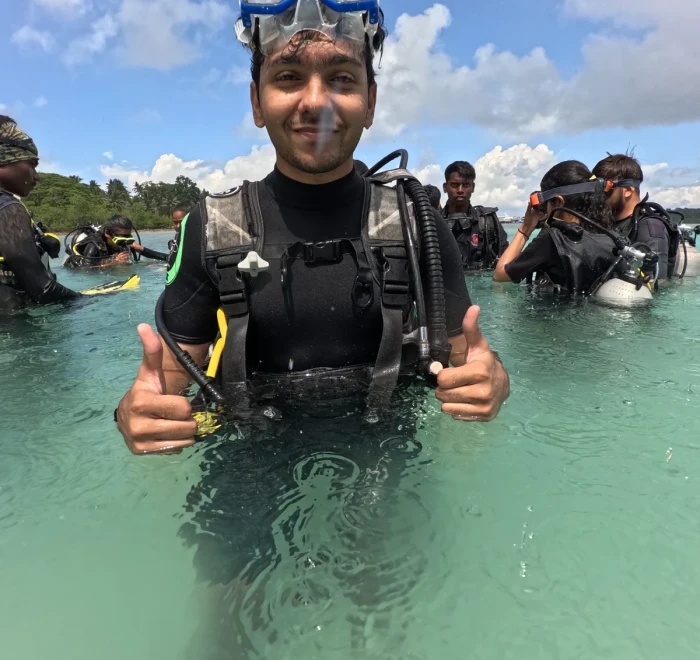 Diver giving thumbs up in the shallows with the group behind