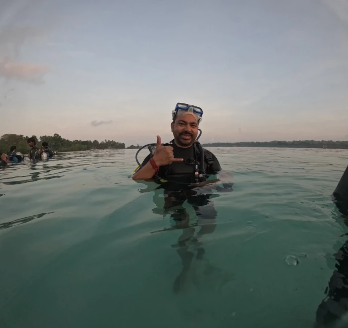 Diver giving a thumbs up in the shallows at sunset