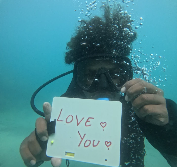 Diver holding a love you slate underwater on a proposal dive