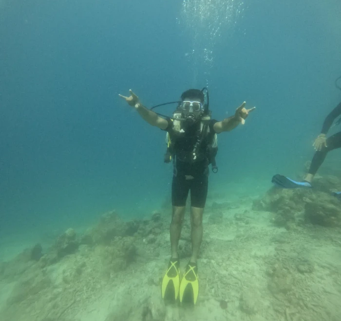 Diver kneeling on the sandy seabed with both arms out