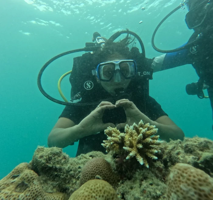 Diver making a heart shape above the coral at the end of the dive